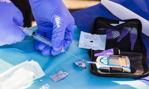 person using disposable syringe put specimen on blue and white glucose meter